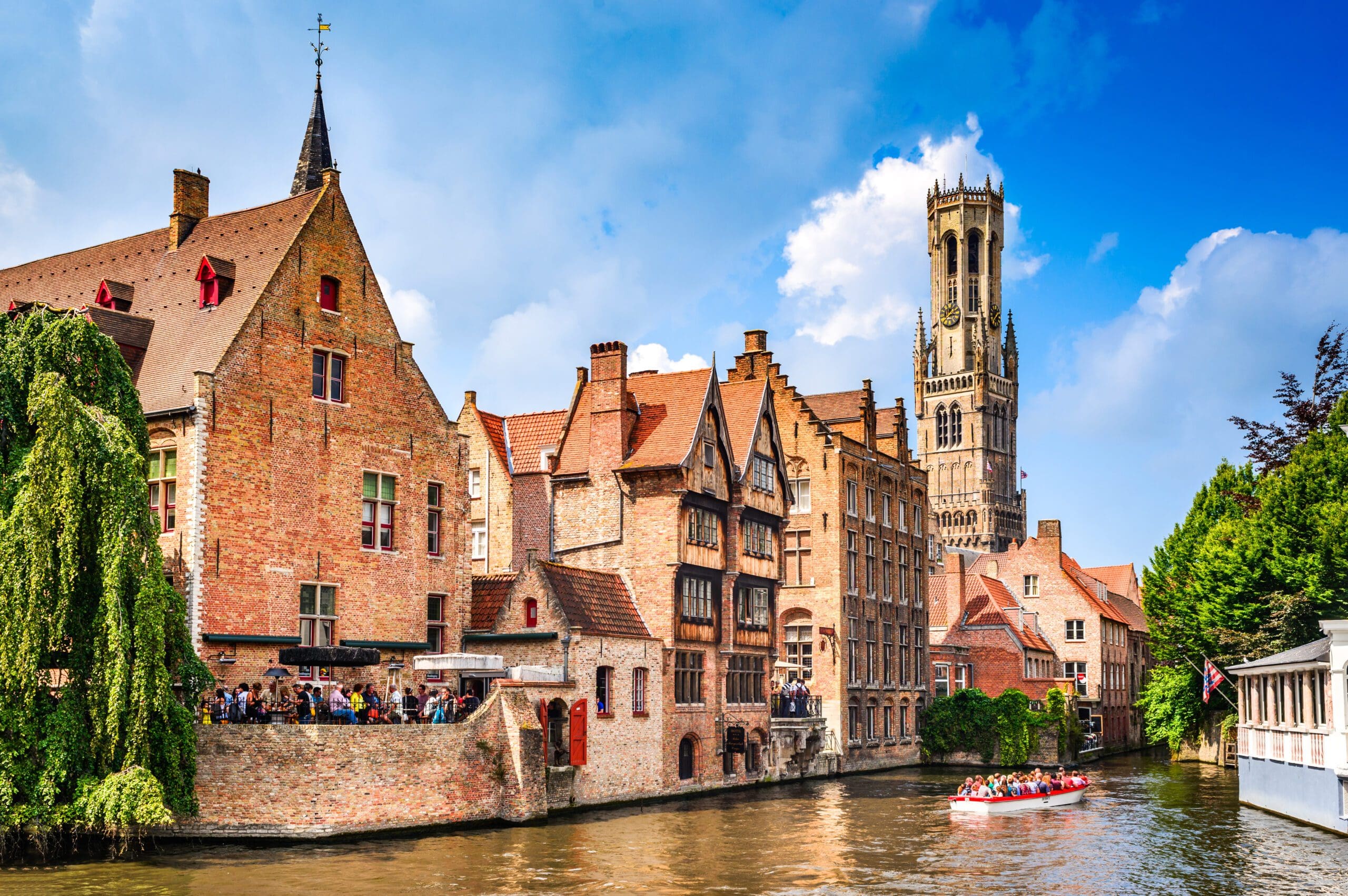 Bruges Canals and river cruise boats with the Belfry and Relais de Bourgondish Cruyce