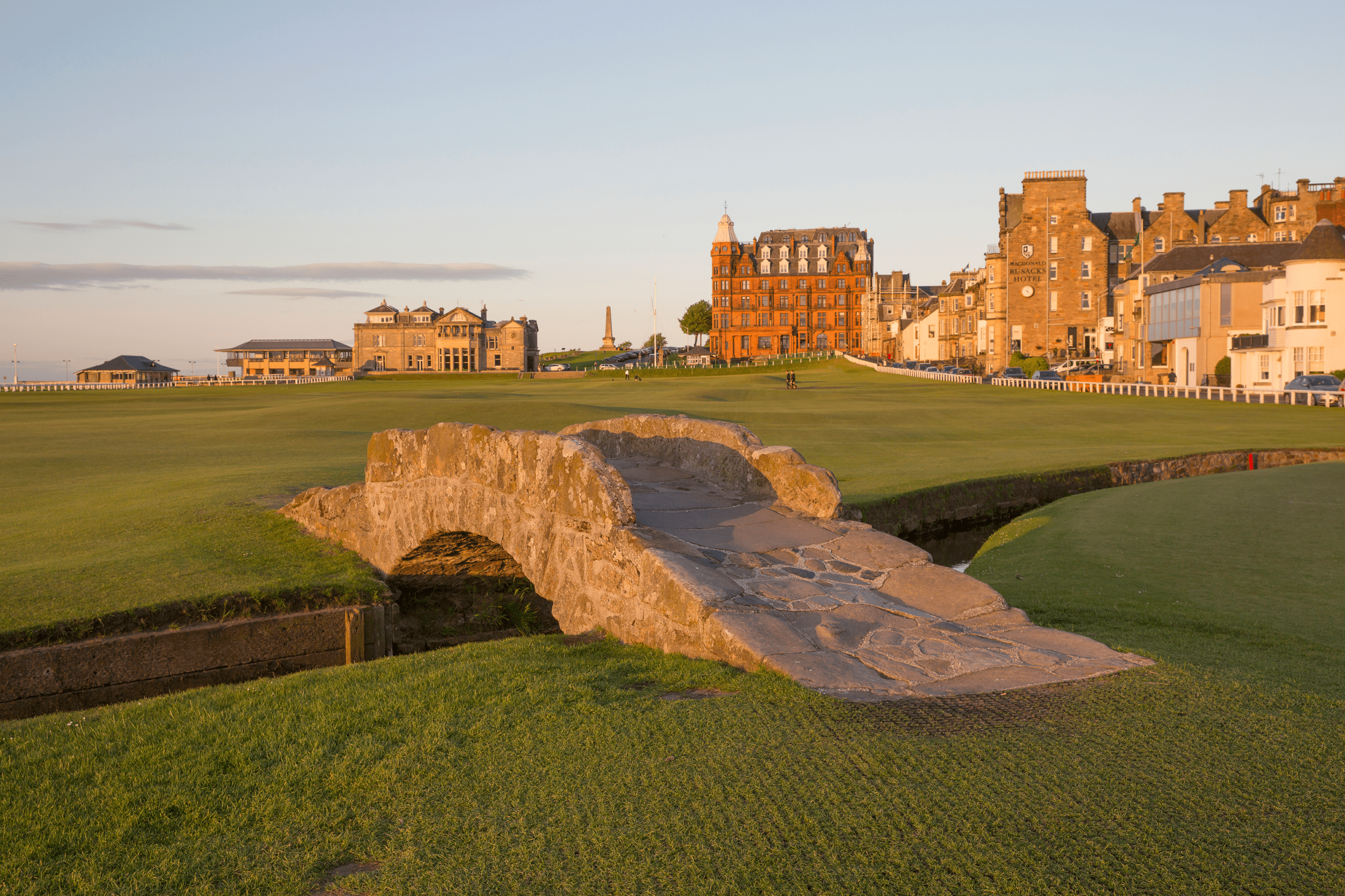 Home of golf during golden hour with the Swilcan Bridge, the R&A Clubhouse and the Hamilton Grand building