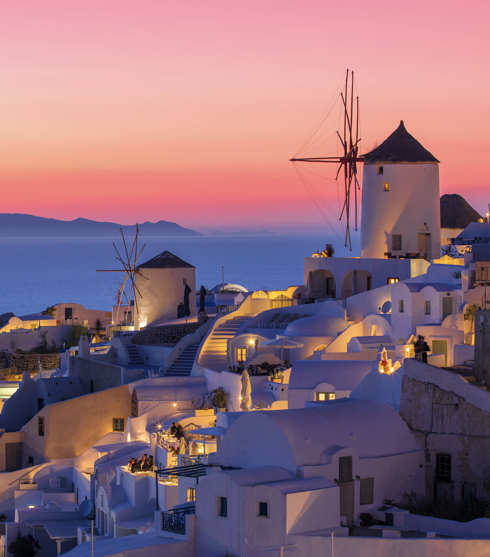 Sunset in Oia with traditional windmills in Santorini Greece